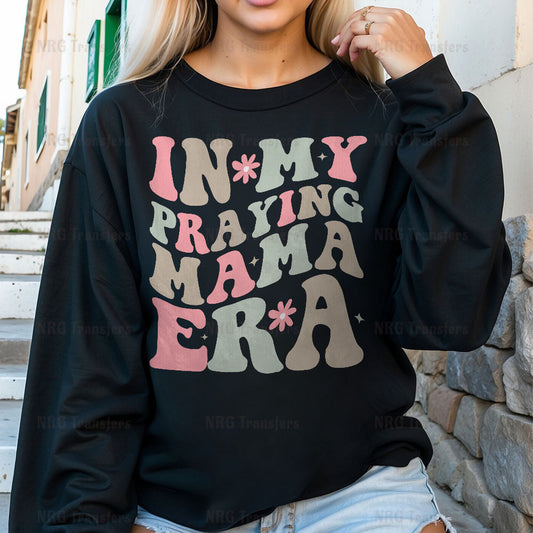 a woman wearing a black sweatshirt that says in my praying mama era